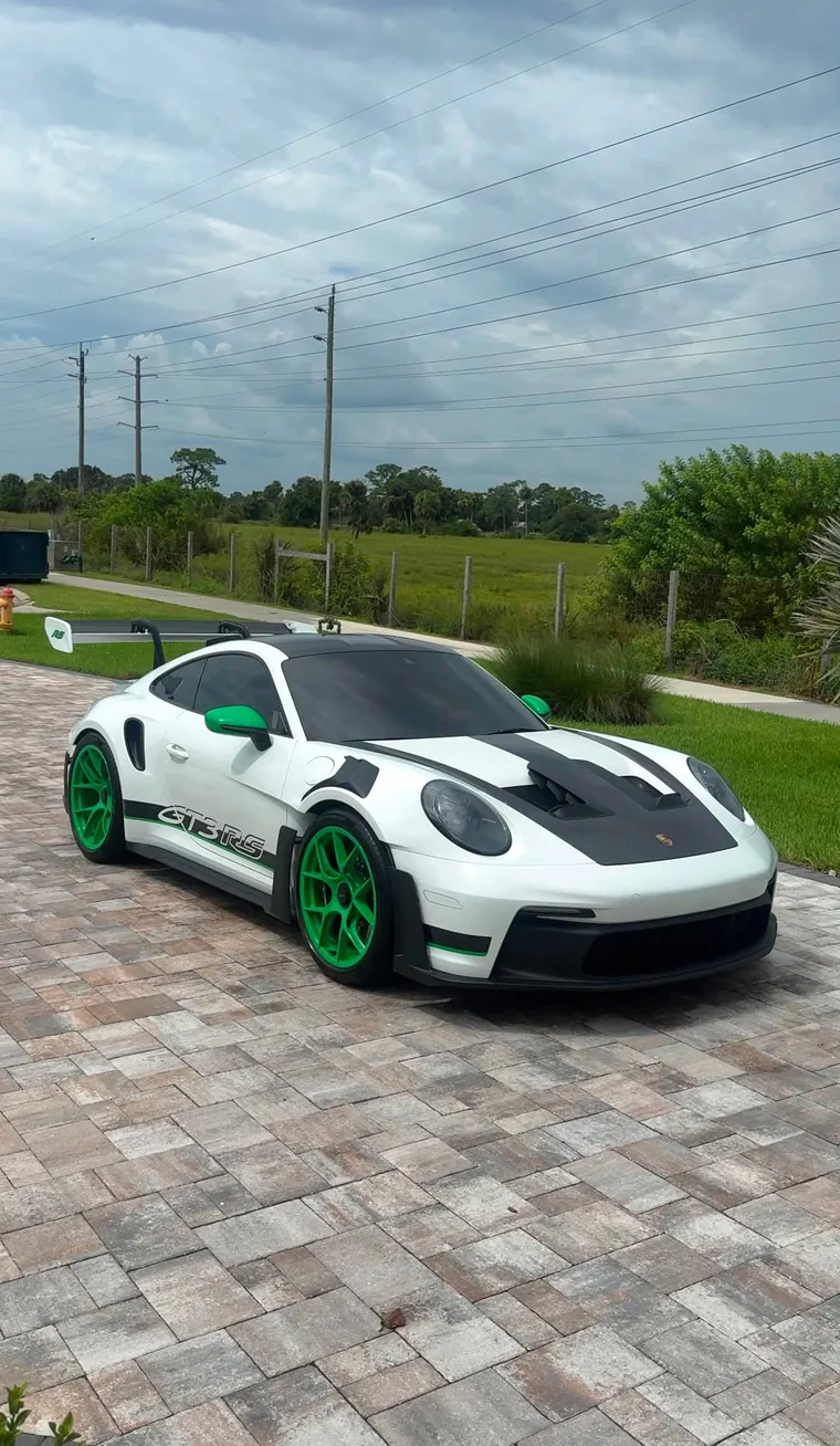 White Porsche 911 GT3 RS with green Weissach wheels on a paver driveway after an exterior detail.
